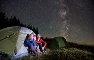 Family looking at a sky full of stars from their camp at night