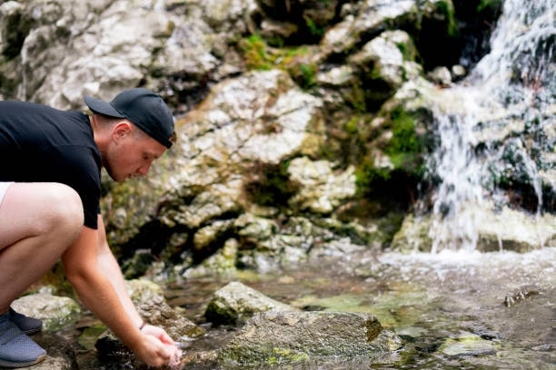 Man drinking clean water from a mountain river