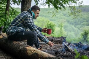Man on a hike sitting by a fire to stay warm