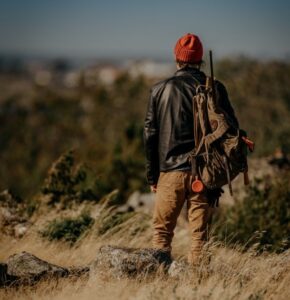 Person carrying a backpack with a gun while exploring the outdoor lifestyle