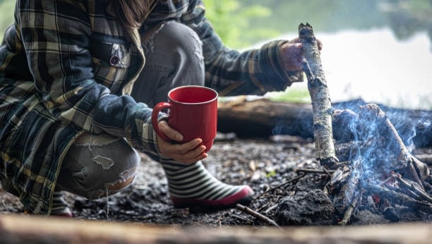 Woman with a cup in her hand as she warms up the fire