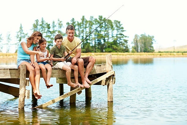 A family of four relaxing while fishing in the lake