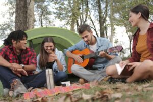 a man playing guitar while camping with friends